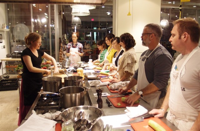 Chef Christianne cutting up an onion as the class looks on.